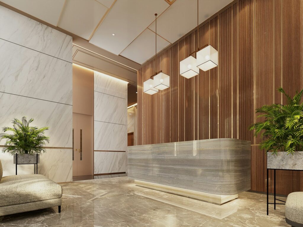Reception desk in pale stone beside a warm wood-slat wall and soft pendant lights