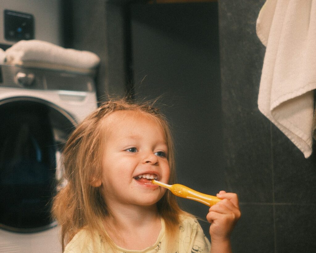 Young child smiling while brushing their teeth