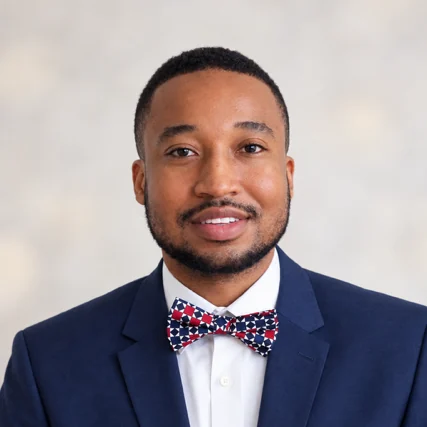 Dr. Nego Roberts, DMD, smiling in a navy suit and patterned bow tie