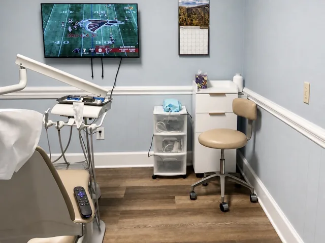 Treatment room with a patient chair, a wall-mounted TV and a clinician's stool