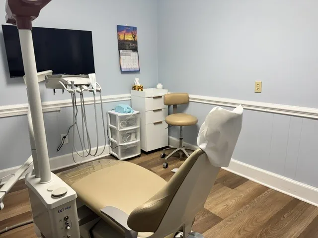 Treatment room with a patient chair, storage cabinets and a clinician's stool