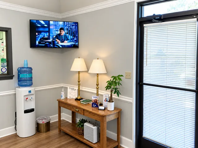 Waiting area with a wooden console table, two lamps, a water cooler and the front entrance